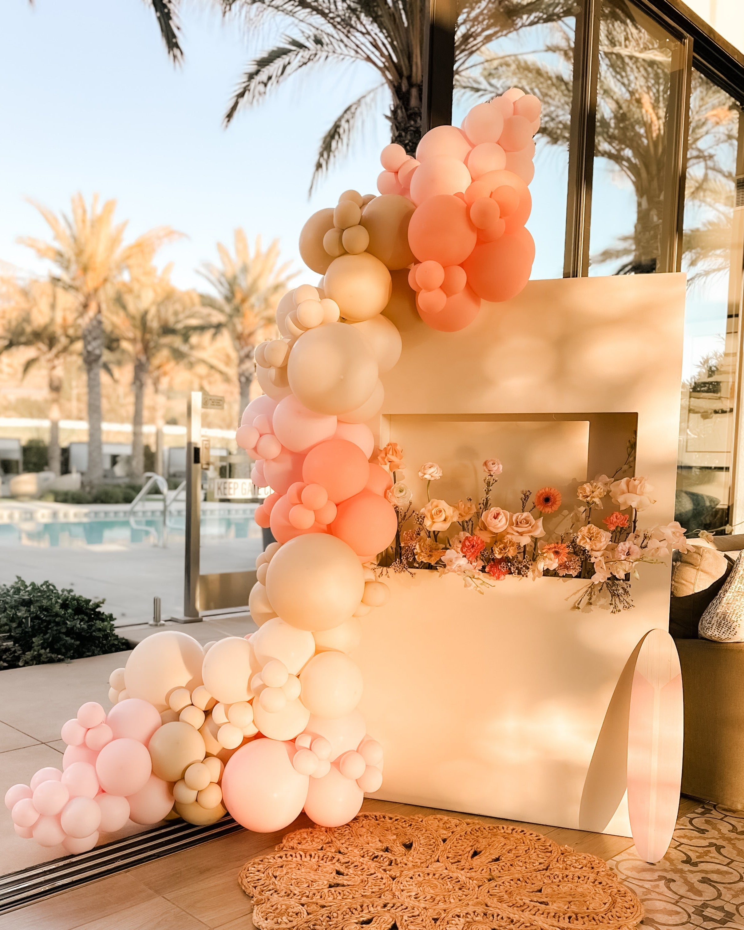 Decorative setup with balloons and flowers on a table by a poolside.